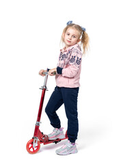 A happy little girl in sports clothes stands with a red scooter, isolated on a white background