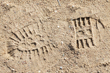 Shoe imprint in sand. Wet sand beach. Trekking shoes print. Walking on sand. Tracking person trail...