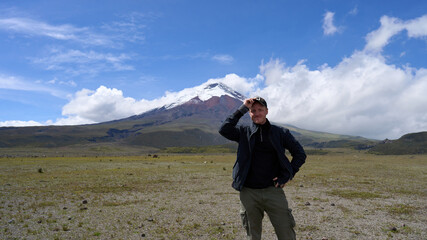 Solo traveler and the Cotopaxi active volcano in Ecuador, South America, hiking tour to the mountain with a snow peak, beautiful landscape.