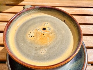 Hot Americano,black coffee placed on an old table, sunlight reflecting