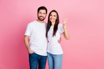 Photo portrait of nice young couple hugging show v-sign wear trendy white outfit isolated on pink color background