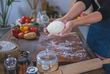 Obraz na płótnie Canvas Woman uses hands to knead pizza dough, prepares and rests the pizza dough before putting it in the oven. To the kitchen concept and homemade pizza