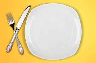 Empty white plate with fork, knife, on the desk
