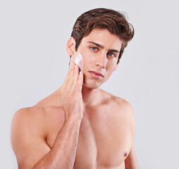 Handsome man, portrait and skincare with face cream for grooming or hygiene on a gray studio...