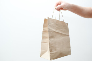 Man hand holding paper bag paper on a white background. Man hand with paper shopping bag. Close up of brown recyclable eco-friendly paper bag