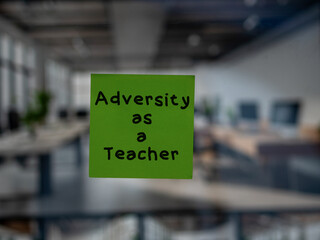 Post note on glass with 'Adversity as a Teacher'.