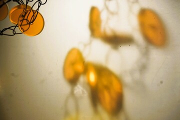 abstraktes Motiv mit Orangebrauner Kette aus Glasperlen vor weiß-beigem Hintergrund mit...