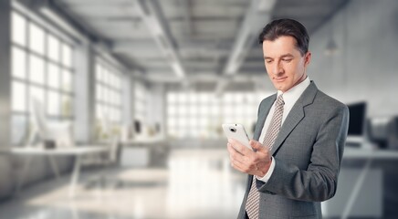 Smiling mature businessman holding phone in office