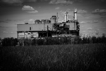 Industrial plant in the middle of a vast prairie in grayscale