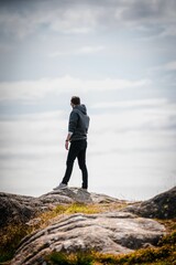 Young adult male hiker on a cliff under a cloudy sky in the countryside