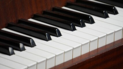 Close-up of an old-fashioned wooden piano keyboard with white and black keys in sharp focus