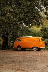 Antique yellow van is parked on a rural dirt road surrounded by trees