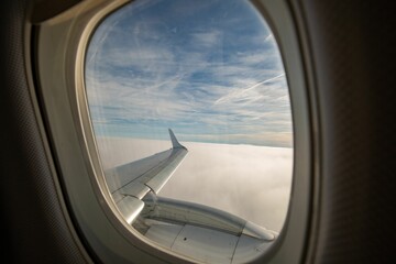 Fototapeta premium Airplane wing with clouds in the background seen through a window