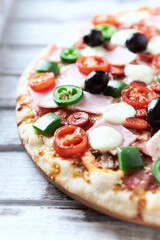 Pizza with ham, mozzarella cheese, cherry tomatoes, green and jalapeno pepper, black olives and fresh basil. Bright background. Close up	