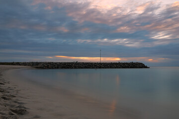 Long exposure photograph at sunset of the ocean and rock wall groyne at Cottesloe Beach, Perth, Western Australia - obrazy, fototapety, plakaty