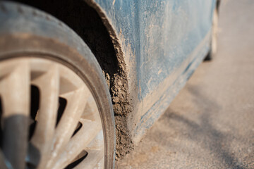 Close-up of dirty car wheel on the asphalting road.