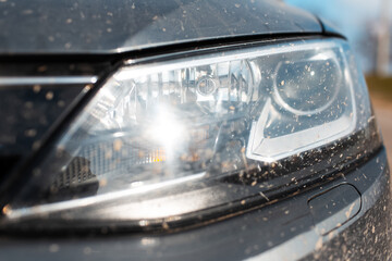 Close-up of headlight of grey dirty car outdoors.