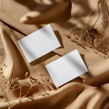 White mockup cards on a natural textured background with fabric, shadows, dried flowers. View from above.