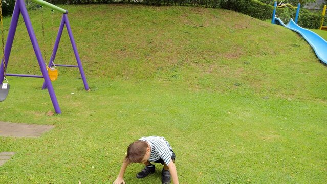 Boy showcases his agility on playground, soaring gracefully through air as he launches himself from swing seat. With fearless creativity, he executes simple trick before landing with poise on grass