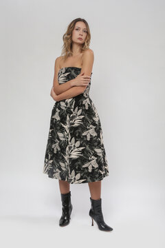 Serie of studio photos of female model in strapless tube top A line midi dress with flared skirt in tropical black floral pattern