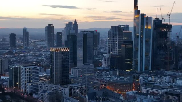 High drone footage of the urban buildings and skyscrapers of Frankfurt city at sunset, Germany