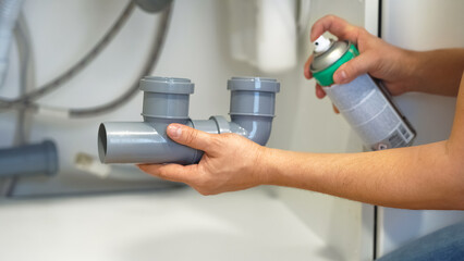 Close up of plumbers hands repair plumbing pipes sewerage using silicone lubricant. Replacement of...