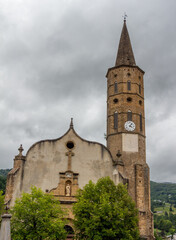 Fototapeta na wymiar View of the tower of the church of Massat, Ariège, Occitanie, France. Village houses.