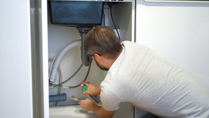 Plumber repairs plumbing pipes sewerage in kitchen sink. Plumbing replacement gasket using silicone...