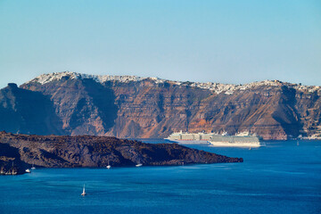 View with cruise ships of the volcanic caldera of Nea Kameni and the village of Imerovigli in the background, from the southwestern part of the island of Santorini
