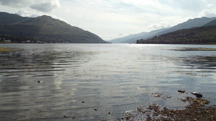 view of a mountain lake from a shore line and rocky beach