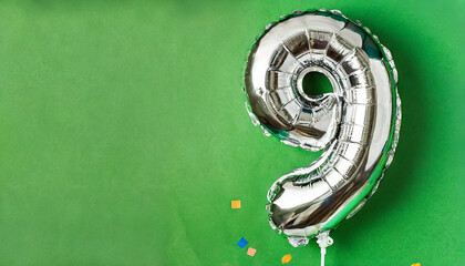 Banner with number 9 silver foil balloon. Nine years anniversary celebration. Green background.