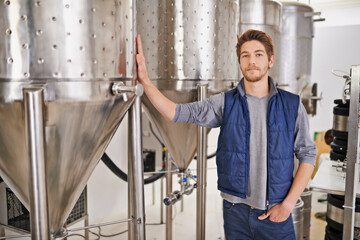 Brewery, man or manufacturing tank with portrait for craft beer, container or production process in factory. Industrial industry, worker or serious in distillery with machine for brewing in warehouse