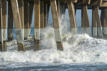 Fotobehang Waves crash against pier foundation in windy weather © Wirestock
