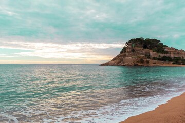 Old castle on a rocky hill on the tropical beach with white sands in Tossa De Mar