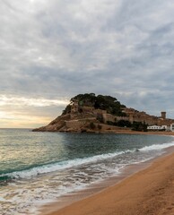 Old castle on a rocky hill on the tropical beach with white sands in Tossa De Mar