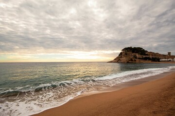 Old castle on a rocky hill on the tropical beach with white sands in Tossa De Mar