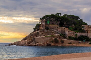 Old castle on a rocky hill on the tropical beach with white sands in Tossa De Mar