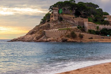 Old castle on a rocky hill on the tropical beach with white sands in Tossa De Mar - obrazy, fototapety, plakaty