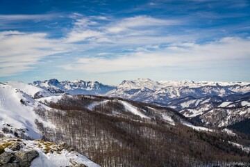 Stunning winter landscape with a blue sky and clouds hovering above mountain peaks, Montenegro