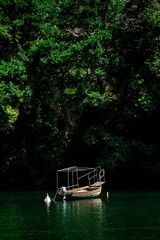 Small boat in the middle of a vast expanse of tranquil pond in Canyon Matka, Skopje - obrazy, fototapety, plakaty