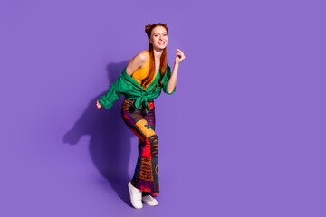 Full length photo of cheerful cute girl wear print trousers stylish shirt dancing at summer party isolated on violet color background