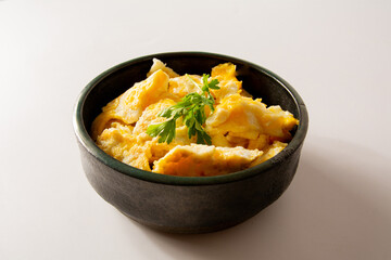 Scrambled eggs in a ceramic bowl in clean white background