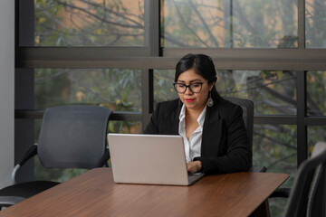 Mexican executive working on her laptop in the office with copy space