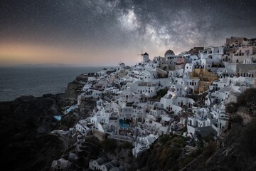 View of Santorini island, with white buildings and cobblestone pathways illuminated by a starry sky