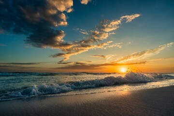 an ocean and some clouds over the shore and a sunset