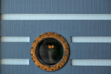 Golden Round Ship's Porthole on a Grey and White Ship Hull.