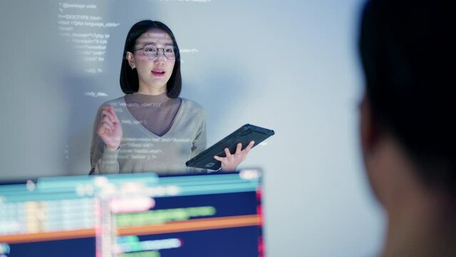 A confident female developer stands presenting HTML code projected on a screen, with the reflection of the code on her glasses.
