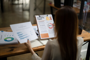 Over-the-shoulder view of a business professional reviewing a detailed marketing report on a...