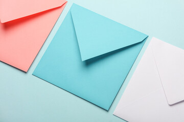 Pink, white and blue square paper envelopes on blue pastel background