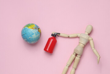 Wooden puppet holding Toy extinguisher and globe on a pastel background. Global warming. Save...